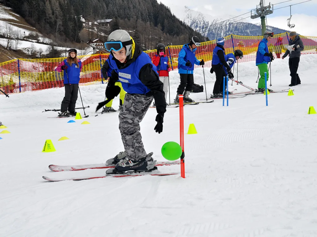 Jugendlicher mit Skibrille übt zwischen den Markierungshütchen.